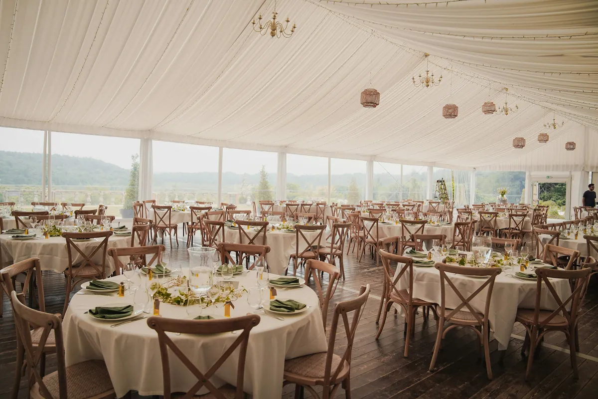 Corporate event tent interior with round dining tables and chairs set for a client reception