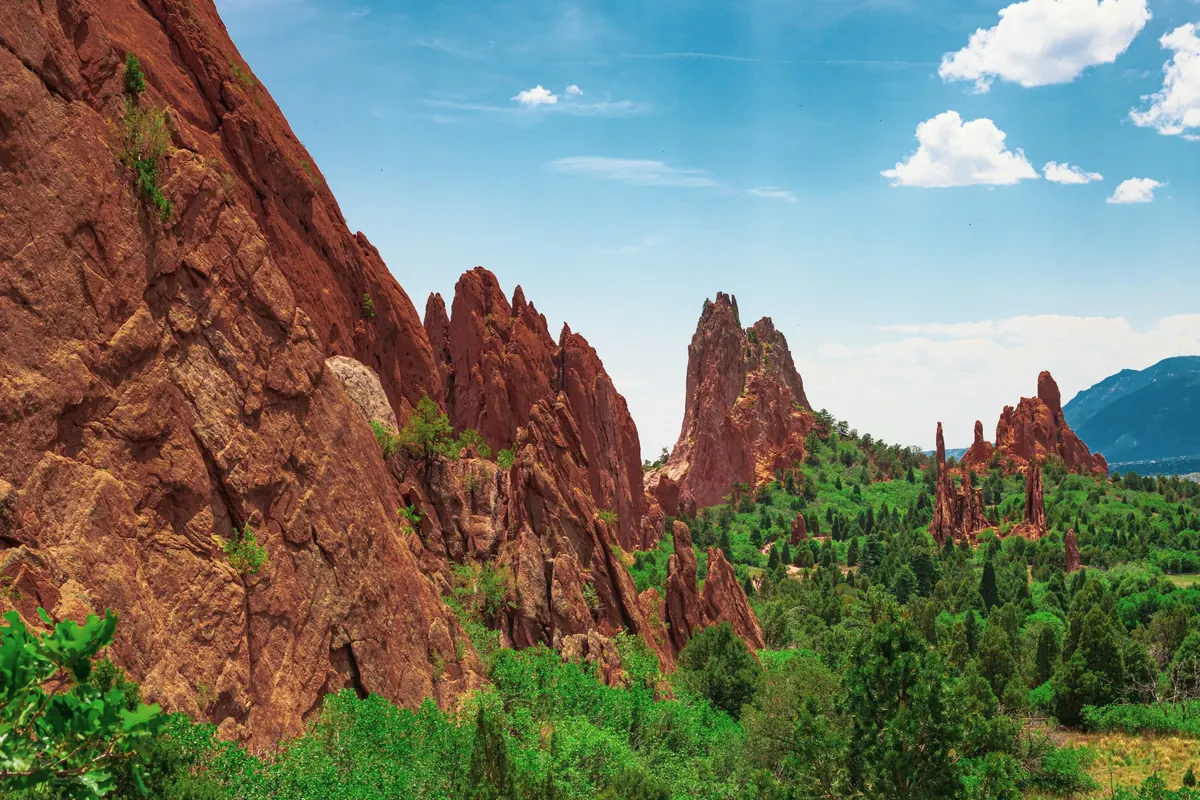 Red sandstone formations at Garden of the Gods in Colorado Springs with green trees and blue sky