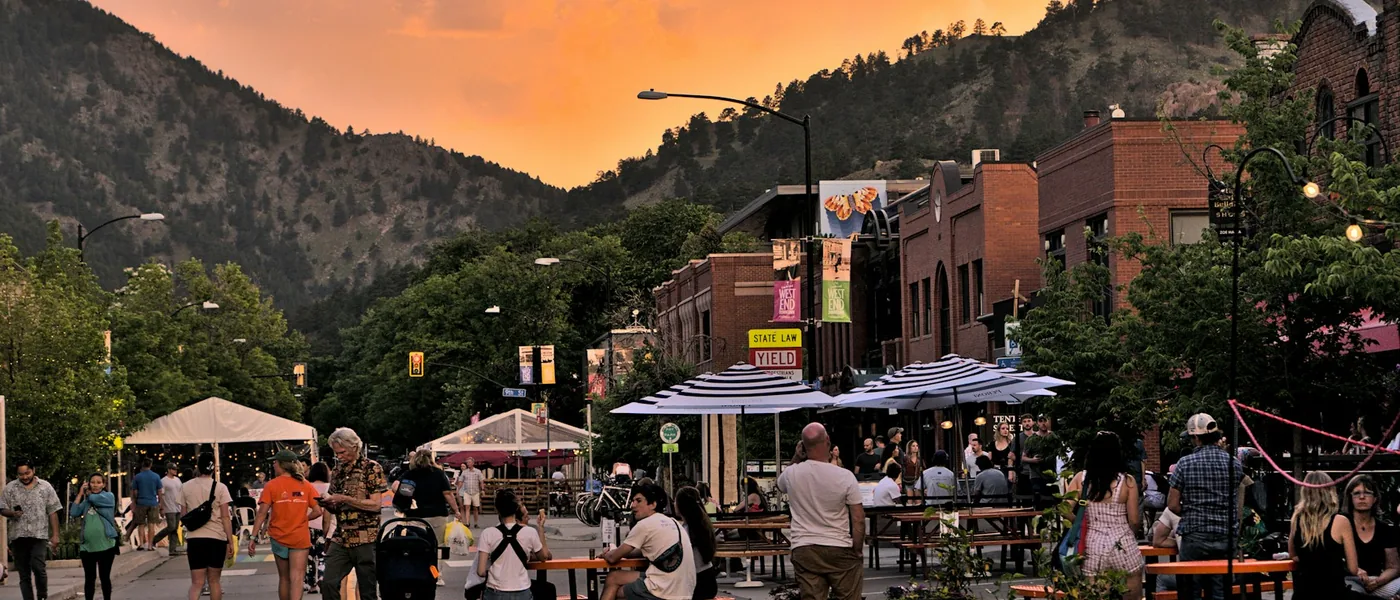 Outdoor dining and canopies on Pearl Street in Boulder with the foothills at sunset