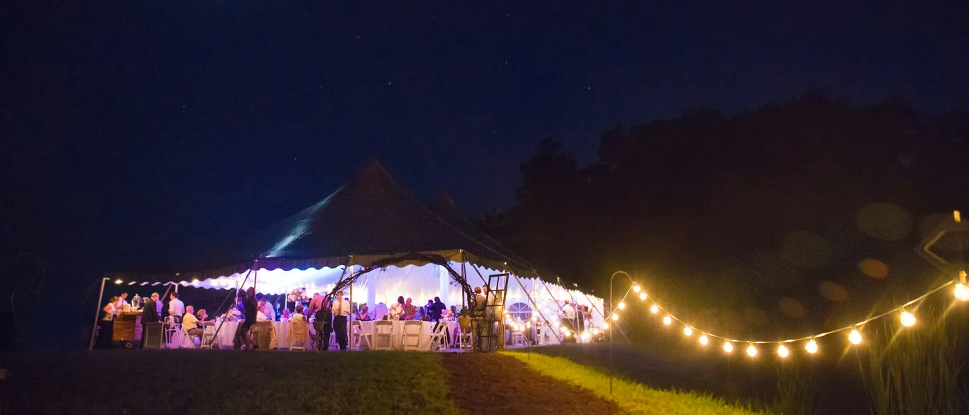 High-peak frame tent reception glowing under string lights at night