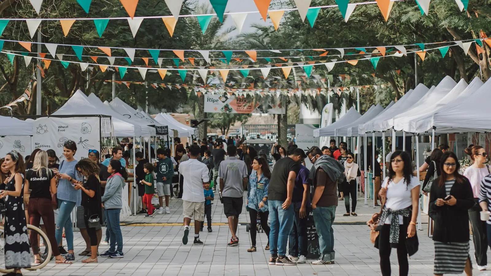 Attendees walking between rows of white vendor tents at an outdoor show